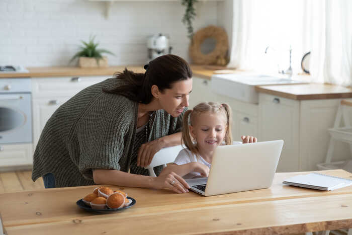 parent helping her child on a laptop