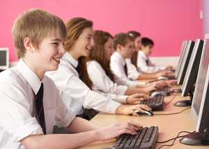 Students working on computers in a classroom with a pink wall.