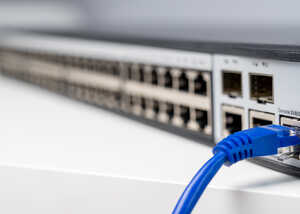 Close-up of a network switch with a blue Ethernet cable connected.