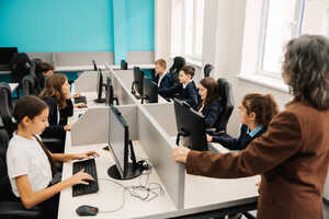 A classroom with students at computers and a teacher observing them.