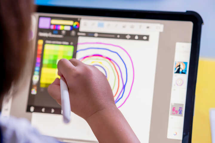A person using a digital tablet and computer for design work at a desk.
