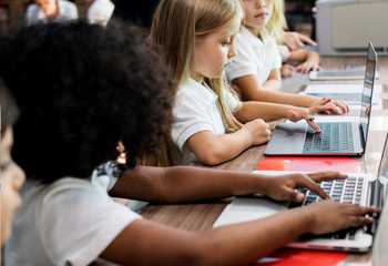 Children in school uniform looking at laptops