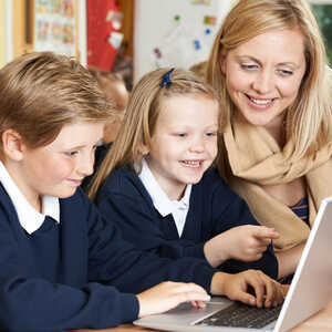 teacher helping students on a laptop