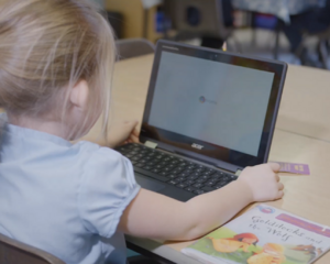 A Computeam IT professional assists a staff member of Pope Francis MAT with Learning Locker at a computer desk